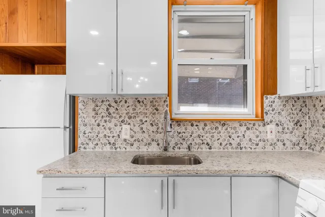 a bathroom with a granite countertop sink a mirror and shower