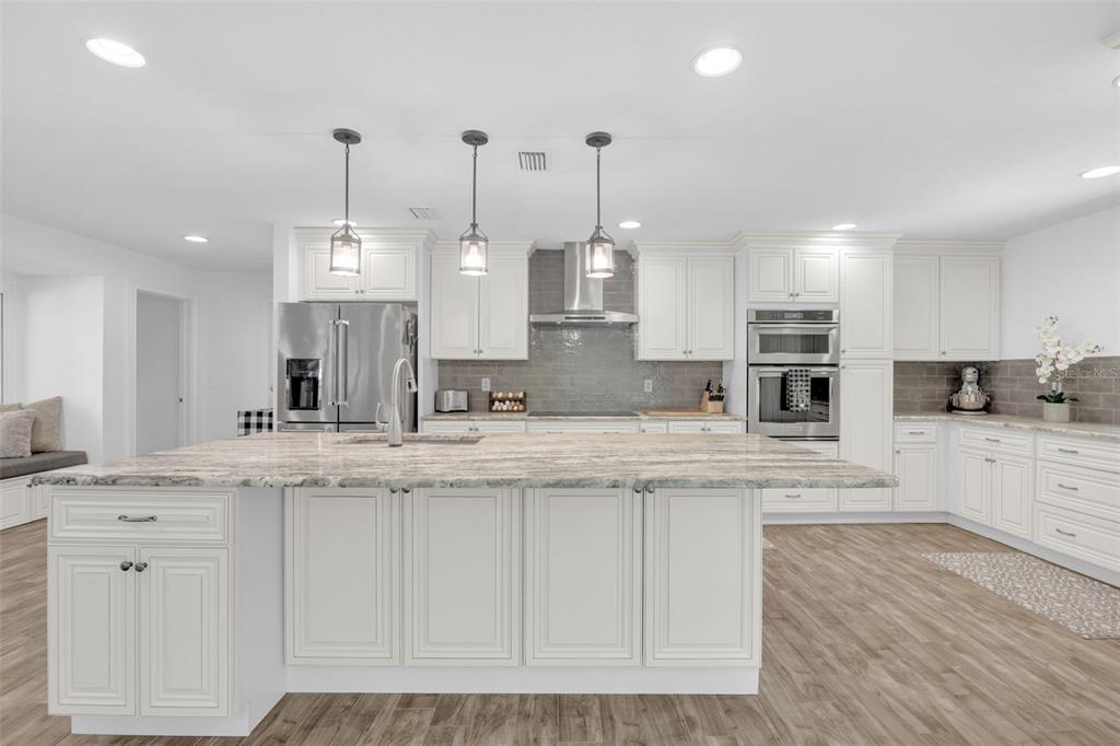 3535 Moores Lake Road Dover, FL 33527 - Photo 11 of 85 The kitchen features a large island with tons of storage and overhead pendant lighting, custom 42" solid wood cabinets, granite countertops, tiled backsplash, matching Kitchen Aid stainless appliances, including a stainless range hood, all new lighting, a large farm sink, and a large wall pantry with pull-out drawers!