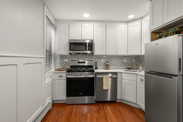 a kitchen with cabinets stainless steel appliances a sink and wooden floor