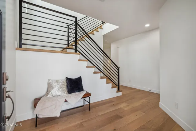 a hallway with wooden floor stairs and a chandelier