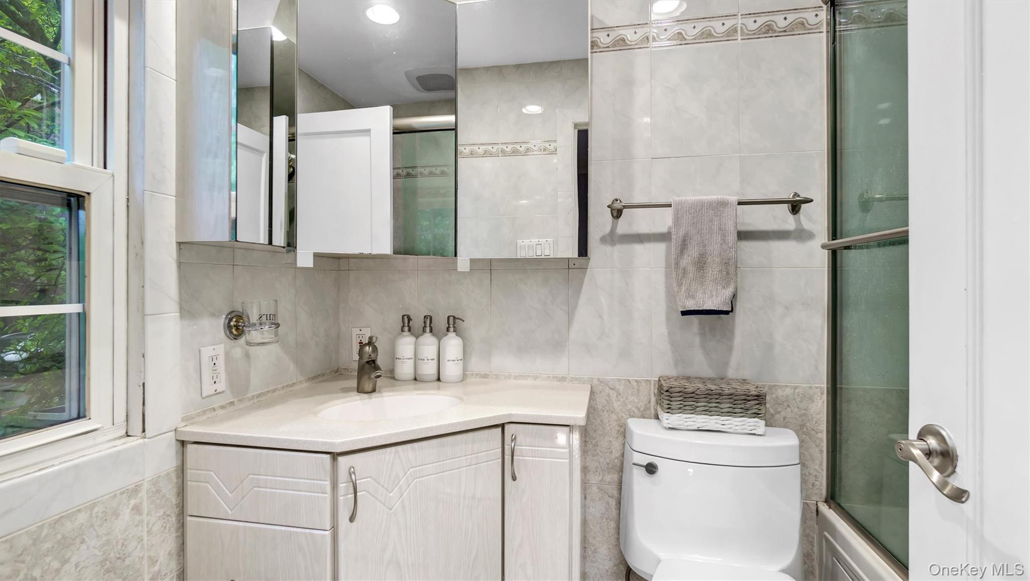 19 Barstow Road, Unit G Great Neck, NY 11021 - Photo 25 of 36 a bathroom with a granite countertop sink a toilet and a mirror