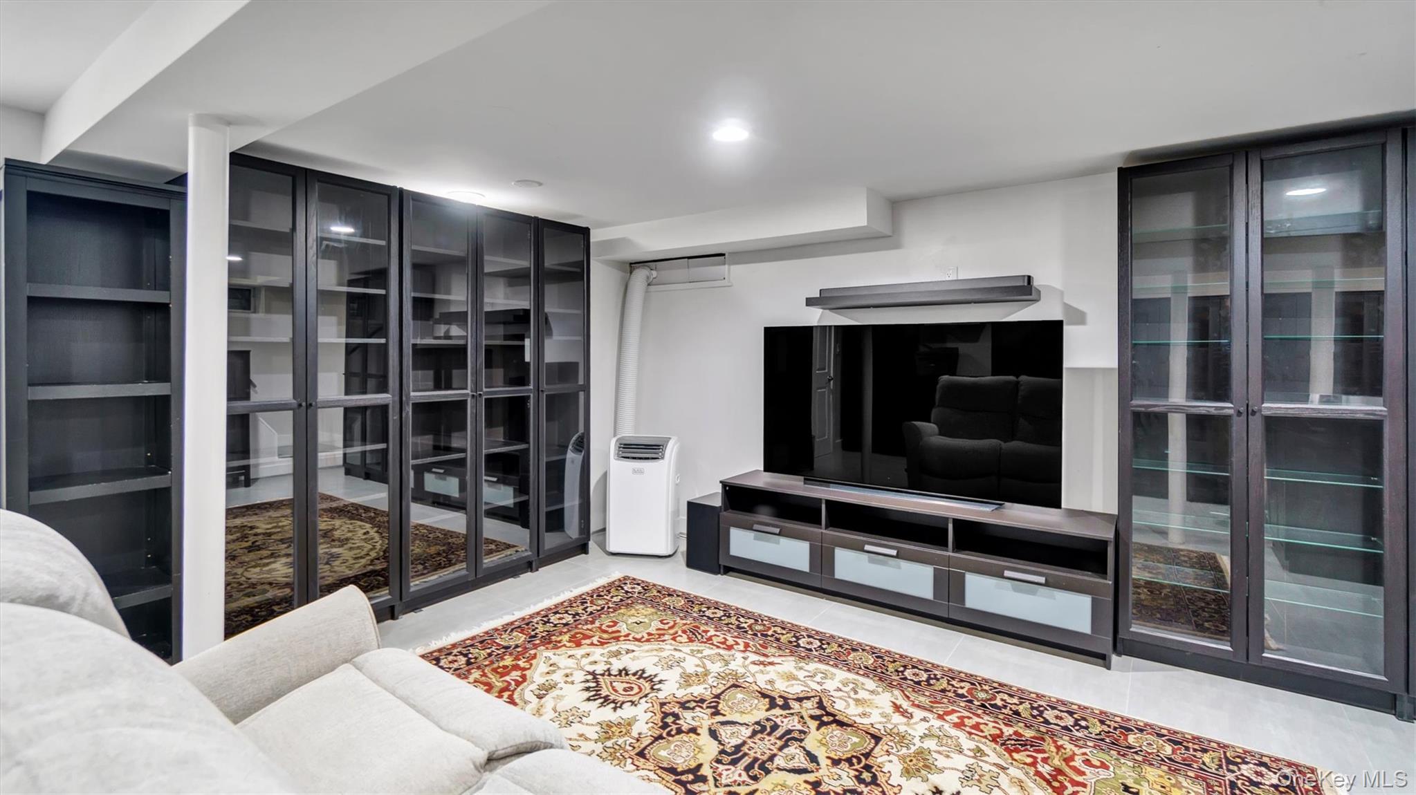 19 Barstow Road, Unit G Great Neck, NY 11021 - Photo 29 of 36 a living room with furniture a flat screen tv and a rug