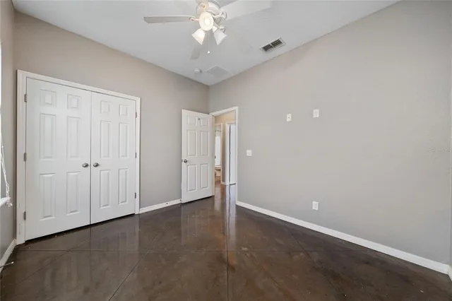 an empty room with closet and a ceiling fan