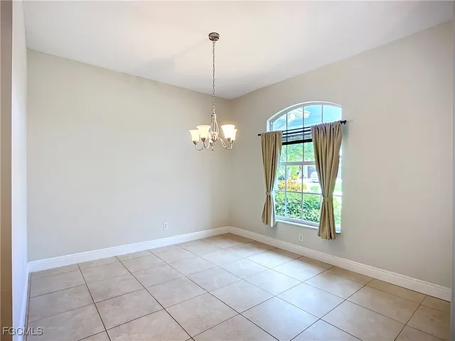 an empty room with chandelier fan and windows