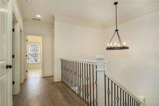 a view of a hallway with wooden floor and a chandelier