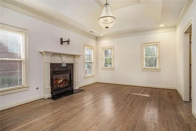 an empty room with windows a fireplace and wooden floor