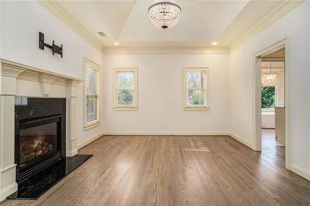 a view of an empty room with wooden floor fireplace and a window