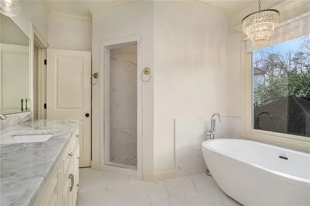 a bathroom with a tub a sink and a large mirror