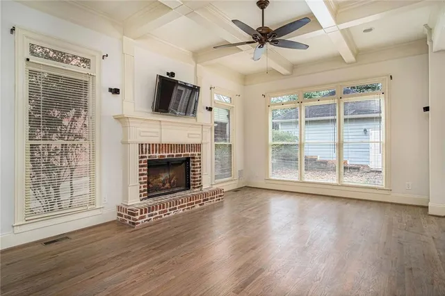 a view of a livingroom with a fireplace a ceiling fan and windows