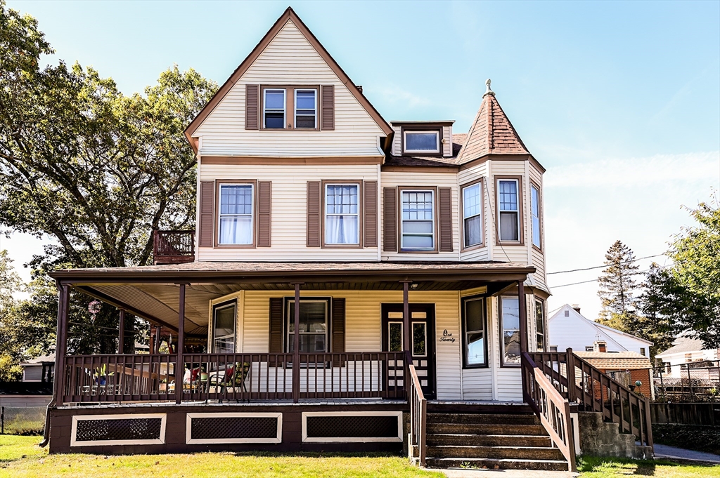 a view of a white house with large windows and a small yard