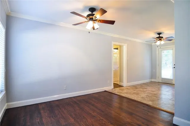 an empty room with wooden floor chandelier fan and windows