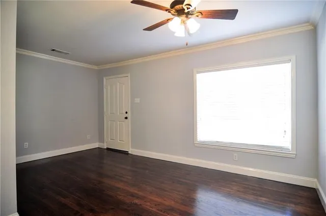 an empty room with wooden floor fan and windows