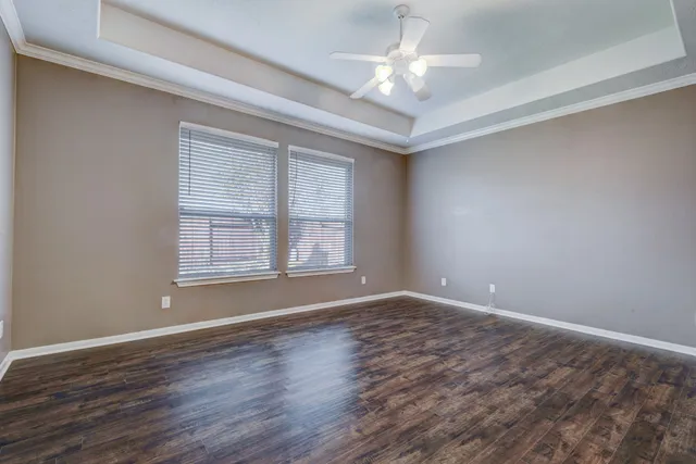 a view of an empty room with a window and wooden floor