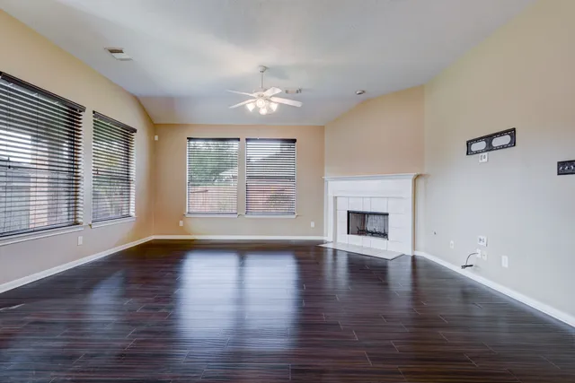 an empty room with wooden floor fireplace and windows