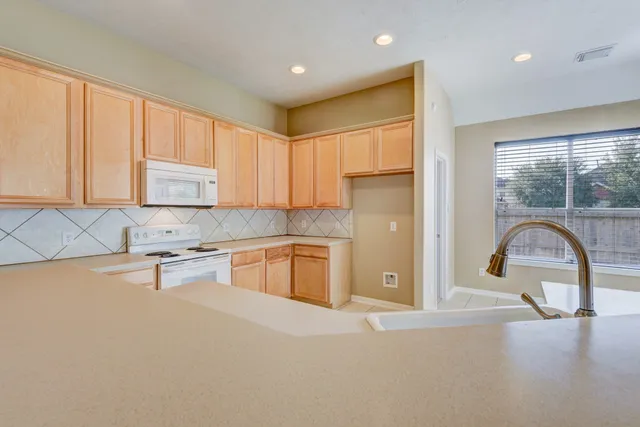 a kitchen with stainless steel appliances granite countertop a stove a sink and a refrigerator with wooden cabinets