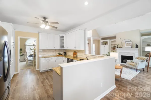 a view of a kitchen with a sink dishwasher a refrigerator with wooden floor and cabinets