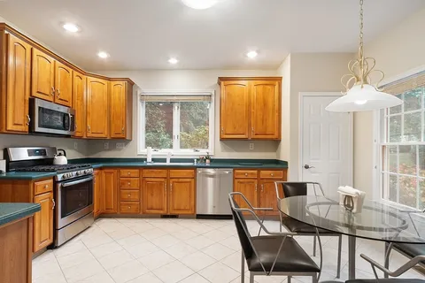 a kitchen with stainless steel appliances granite countertop wooden cabinets a stove a sink a dining table and chairs