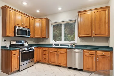 a kitchen with granite countertop cabinets stainless steel appliances a sink and a window
