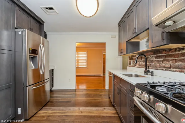 a kitchen with stainless steel appliances granite countertop a refrigerator a stove and a sink