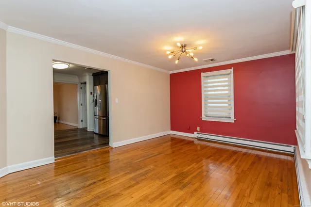 a view of an empty room with window and wooden floor