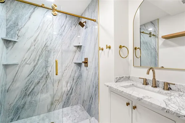 a bathroom with a granite countertop shower sink vanity and mirror