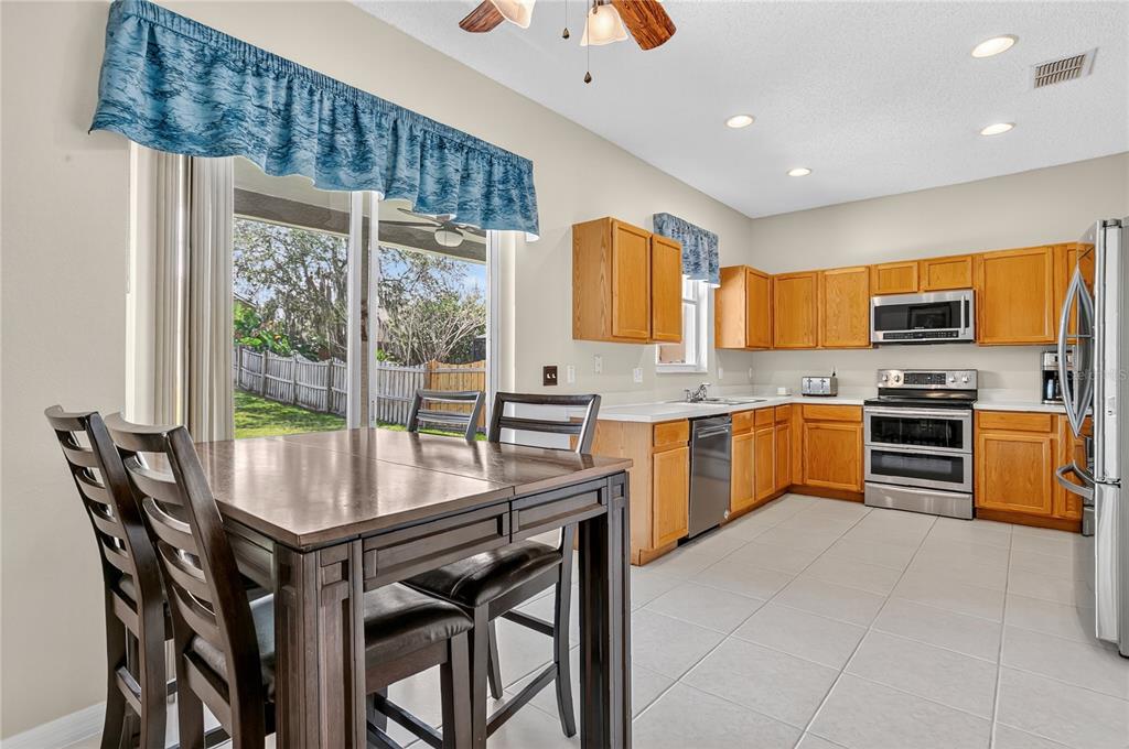223 Tavestock Loop Winter Springs, FL 32708 - Photo 6 of 27 a kitchen with stainless steel appliances granite countertop a stove top oven a refrigerator a sink and a dining table with garden view
