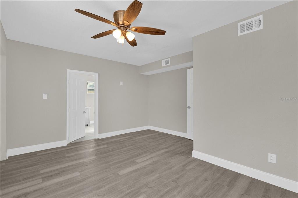 923 Ferndell Road Orlando, FL 32808 - Photo 17 of 42 an empty room with wooden floor and ceiling fan