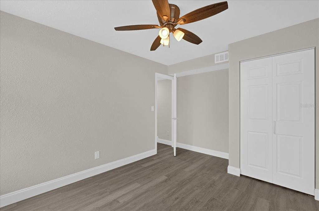 923 Ferndell Road Orlando, FL 32808 - Photo 19 of 42 an empty room with wooden floor and ceiling fan