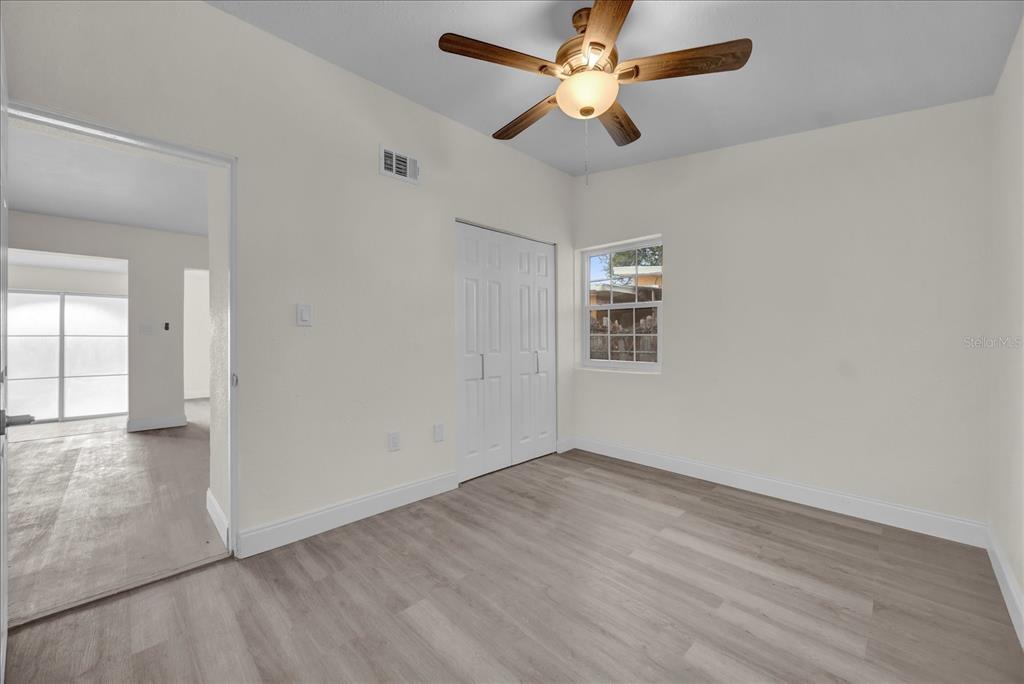 923 Ferndell Road Orlando, FL 32808 - Photo 30 of 42 an empty room with wooden floor chandelier fan and windows