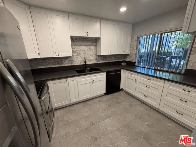 a kitchen with granite countertop white cabinets and sink