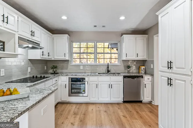 a kitchen with stainless steel appliances granite countertop a stove a sink and a white cabinets