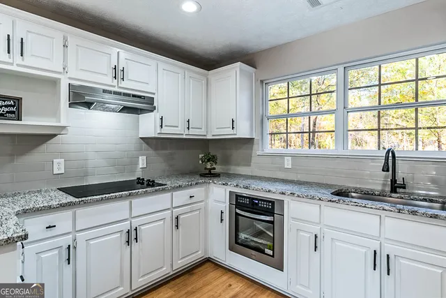 a kitchen with granite countertop white cabinets and white appliances
