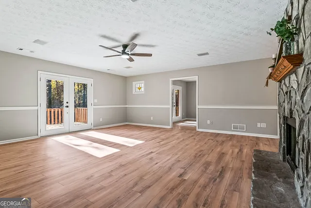 a view of an empty room with a window and wooden floor