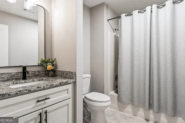 a bathroom with a granite countertop sink toilet and mirror