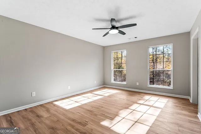 a view of an empty room with a window and wooden floor
