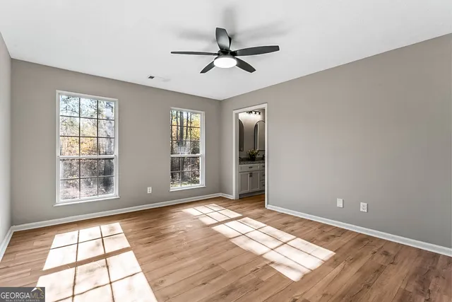 a view of empty room with wooden floor and fan