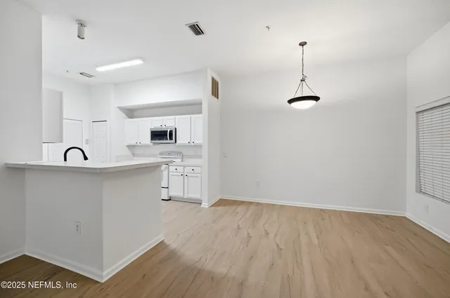an empty room with wooden floor chandelier fan and windows