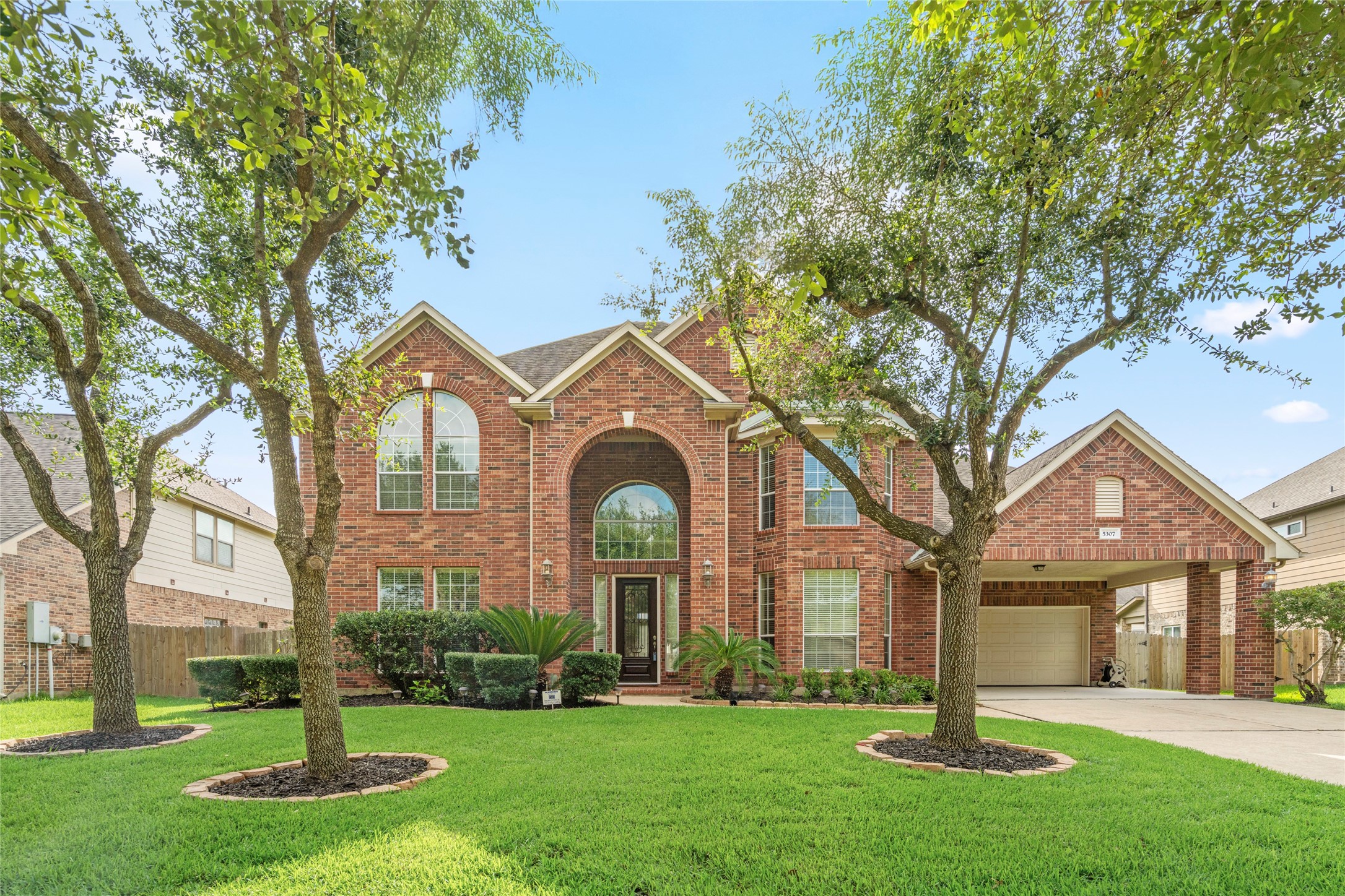 5307 Amber Sky Lane Rosharon, TX 77583 - Photo 3 of 50 Bathed in daylight, this elegant brick residence showcases manicured landscaping, a grand arched entry, and abundant natural light pouring through oversized windows, a welcoming first impression for the most discerning buyer.