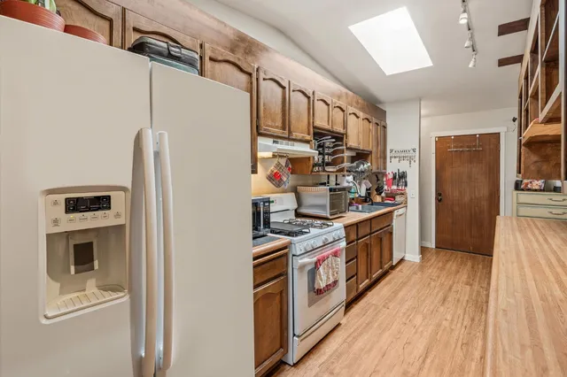 a kitchen with stainless steel appliances granite countertop a refrigerator a stove and a wooden floors