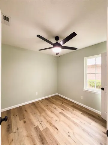 an empty room with a window and ceiling fan
