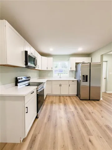 a kitchen with stainless steel appliances granite countertop a stove top oven a sink dishwasher and a refrigerator with wooden floor