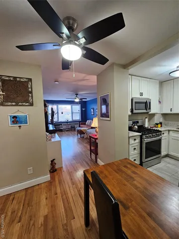 a kitchen with stainless steel appliances kitchen island granite countertop a refrigerator a stove top oven a sink dishwasher and a dining table with wooden floor