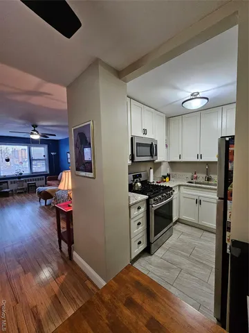a kitchen with stainless steel appliances wooden floors and view living room