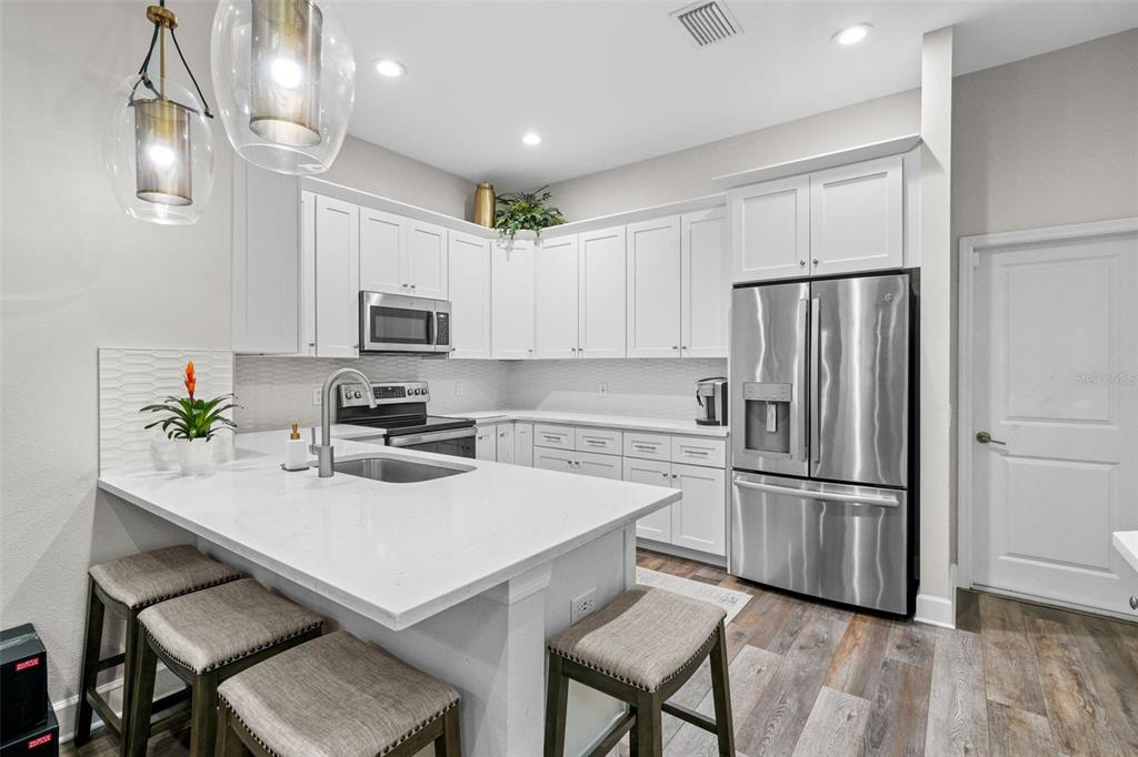 1404 Ridge Terrace Tarpon Springs, FL 34689 - Photo 7 of 38 a kitchen with a refrigerator a stove a microwave and island with wooden floor