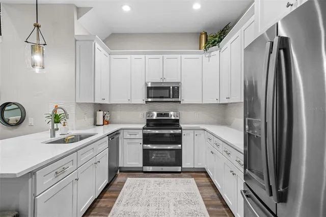 a kitchen with granite countertop white cabinets and stainless steel appliances