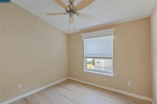 an empty room with a window and a fan