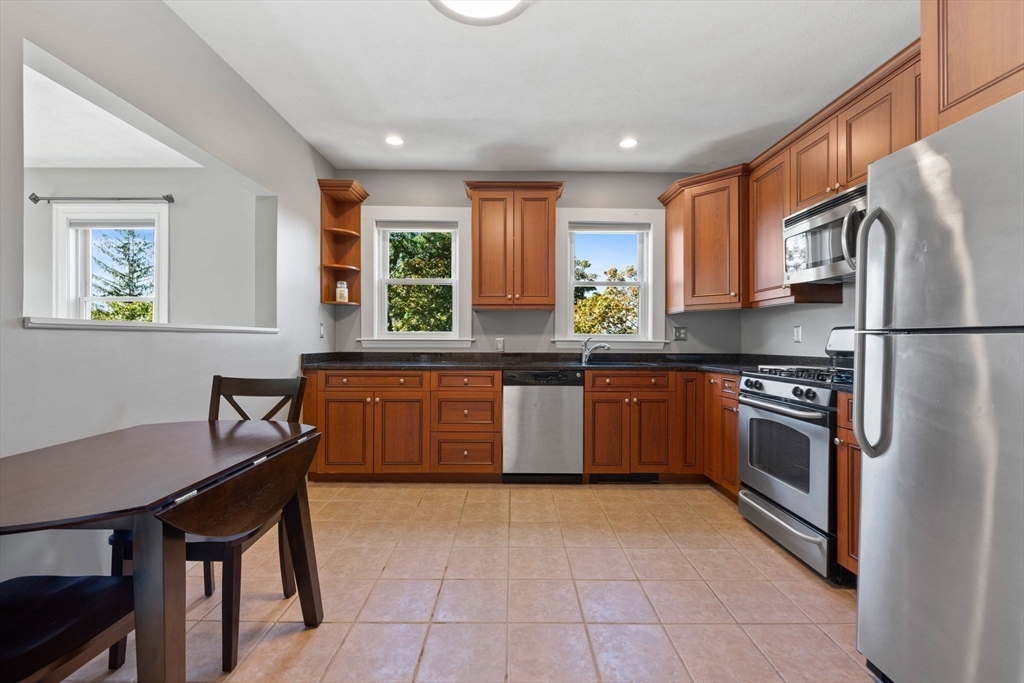 314 Water Street, Unit 5 Wakefield, MA 01880 - Photo 2 of 20 a kitchen with stainless steel appliances granite countertop a stove a sink dishwasher a refrigerator and a dining table with wooden cabinet