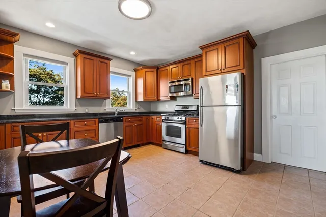 a kitchen with stainless steel appliances granite countertop a refrigerator a stove a sink a dining table and chairs