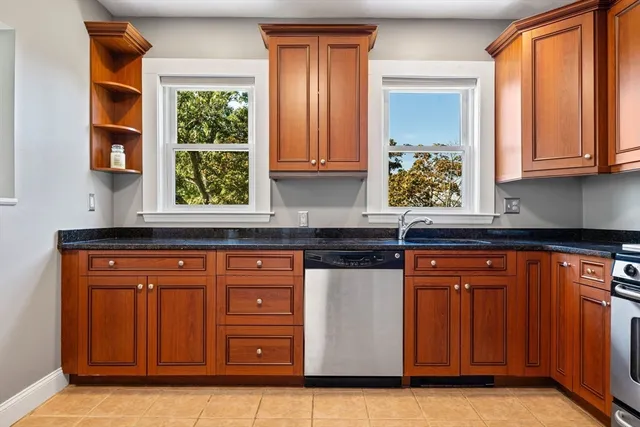 a kitchen with stainless steel appliances granite countertop wooden cabinets a sink and a large window