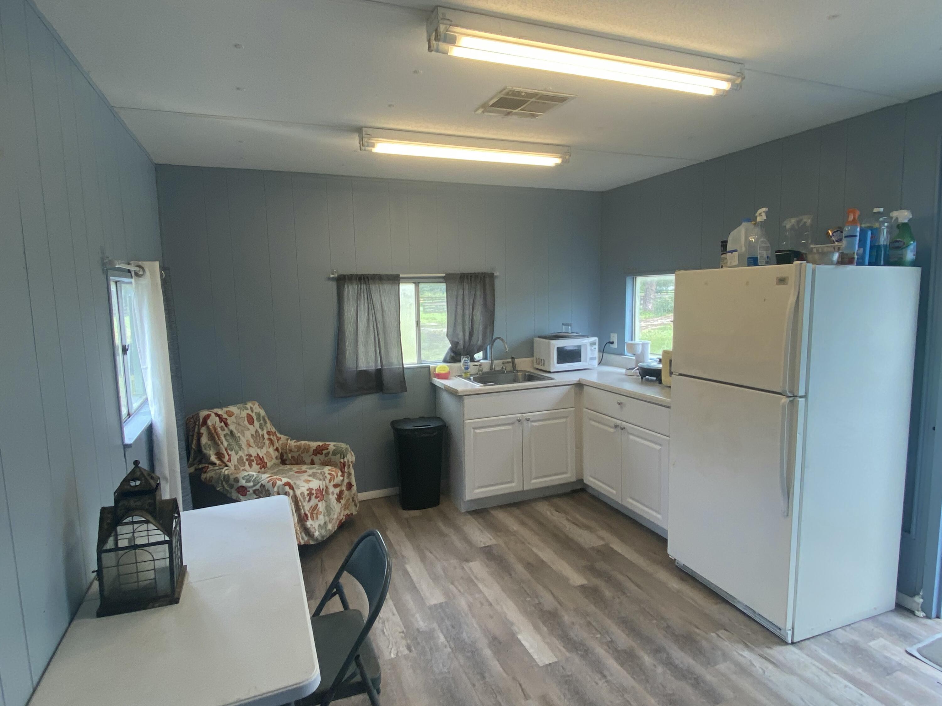 2141 B Road, Unit 4 Loxahatchee Groves, FL 33470 - Photo 13 of 43 a kitchen with a refrigerator and white cabinets